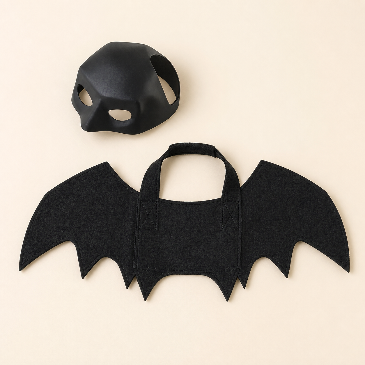 Representational studio flat lay of the separate black cowl mask and connected wing harness